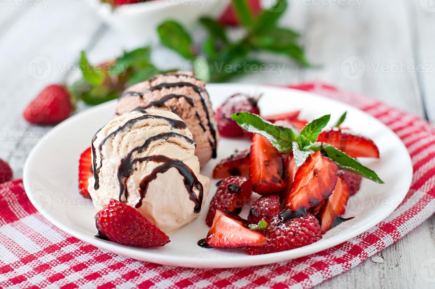 Ice cream with strawberries and chocolate on a white plate photo