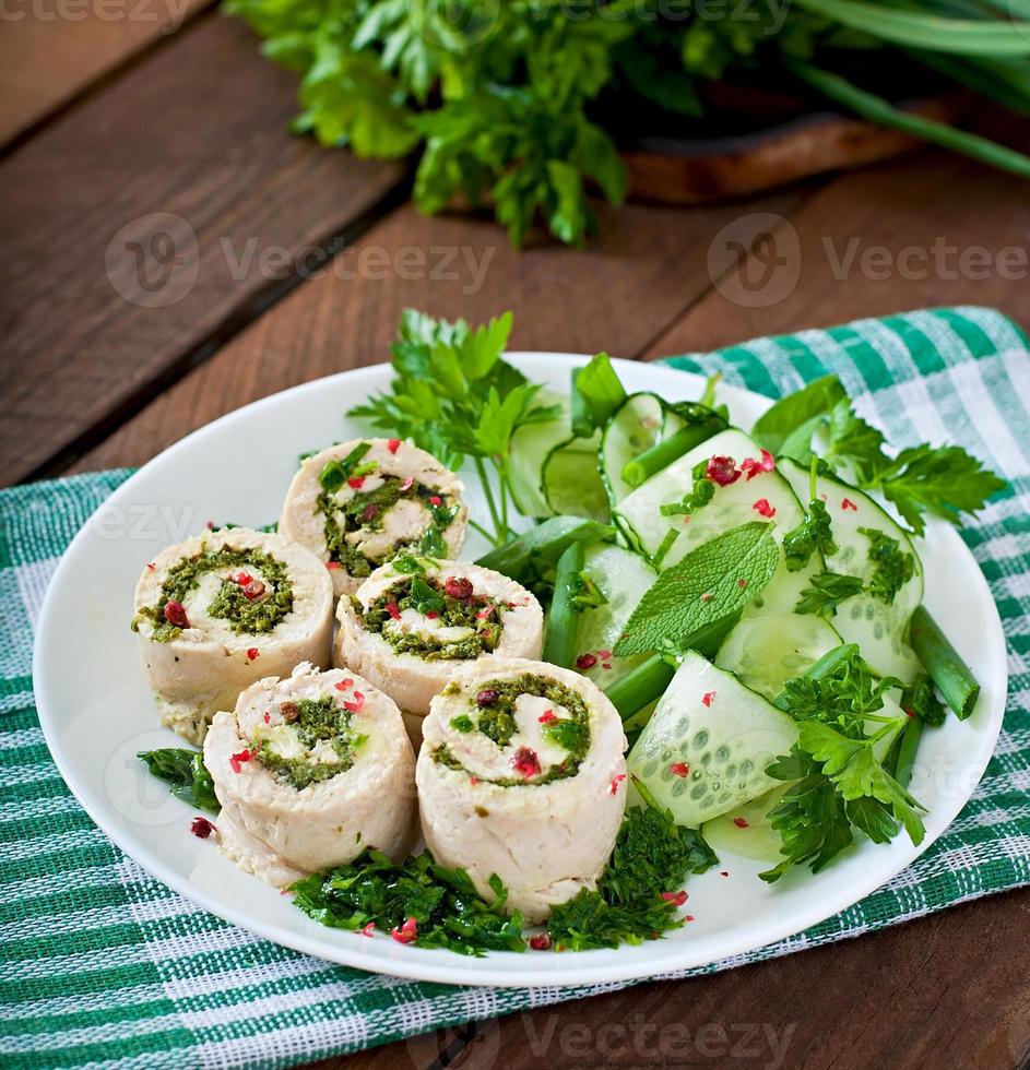 Steamed chicken rolls with greens and fresh vegetable salad on a brown plate photo