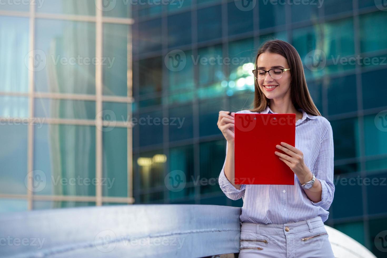 Executive business woman with clipboard against the urban background photo