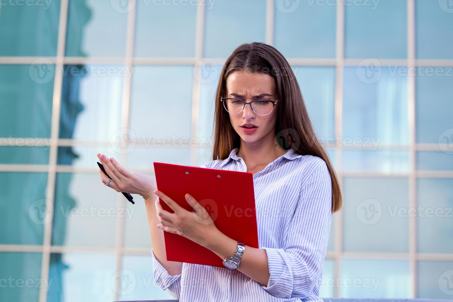 Businesswoman in formal wear having trouble with contracts on clipboard. Businesswoman angry abount about paperwork failure at workplace, executives having conflict over responsibility for bad work photo