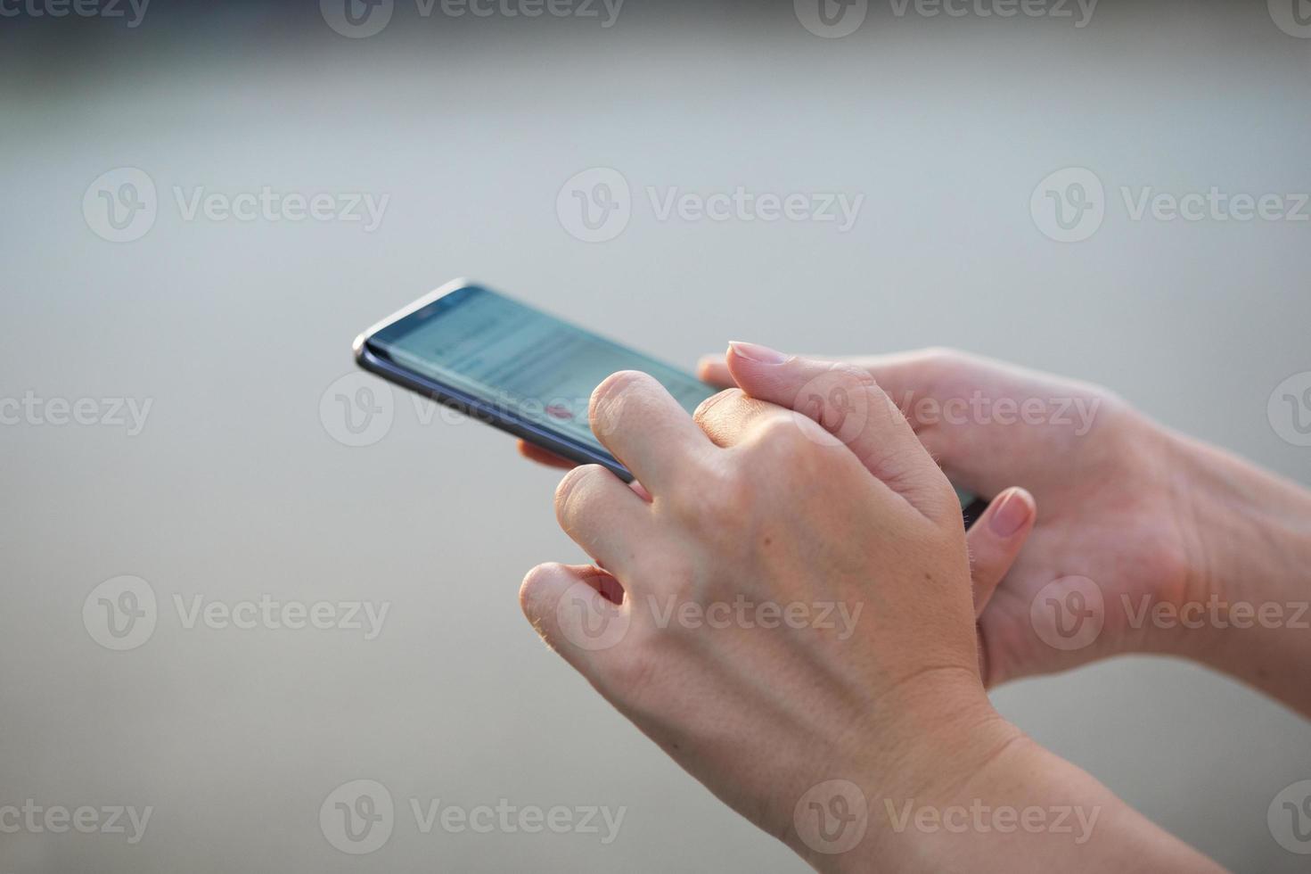 primer plano de las manos de las mujeres sosteniendo un teléfono celular con una pantalla de espacio en blanco para su mensaje de texto publicitario o contenido promocional foto