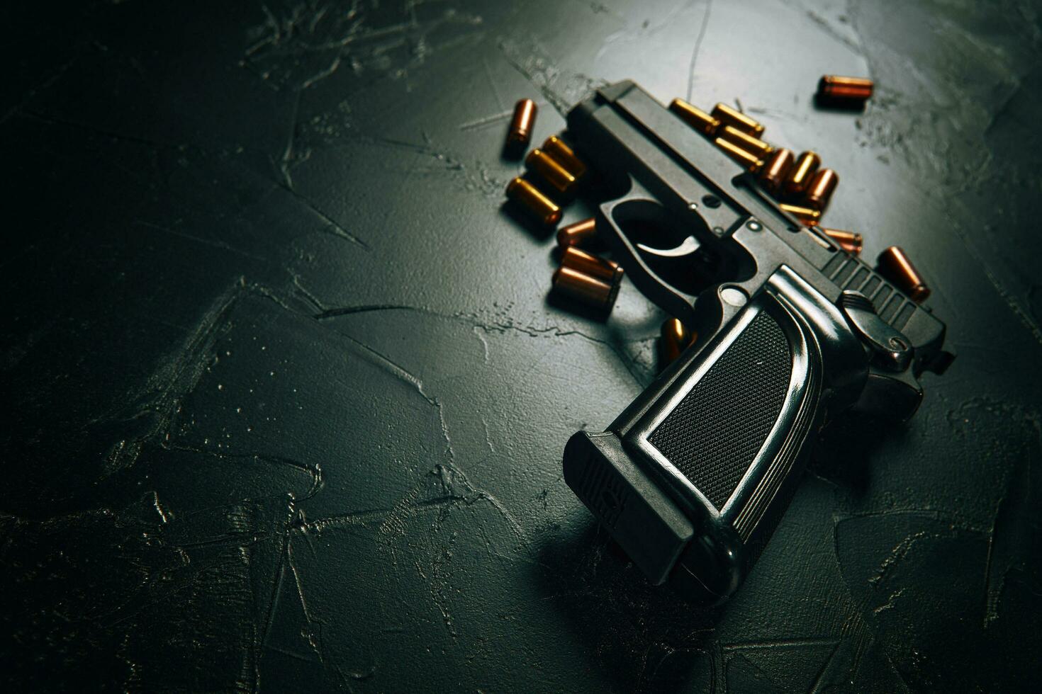 Gun with cartridges on dark concrete table. photo