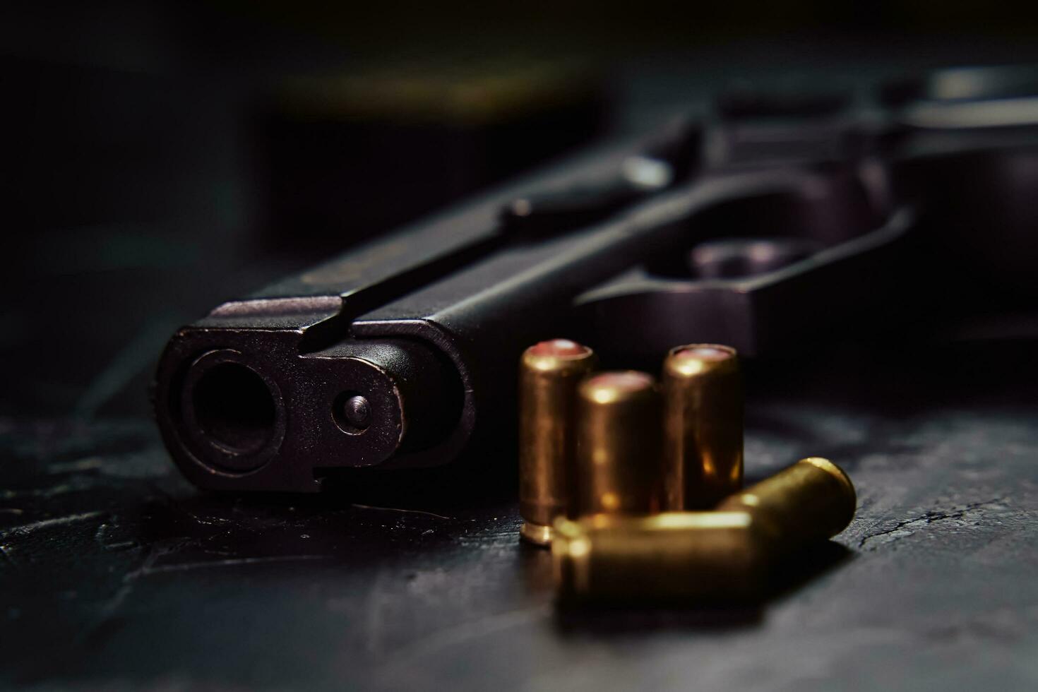 Pistol with cartridges on black concrete table. photo