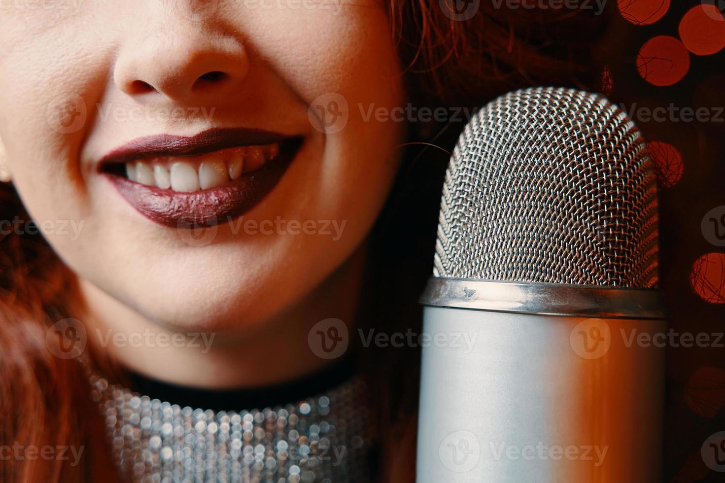 sonriente cantante femenina y micrófono retro sobre fondo de desenfoque de bokeh. foto