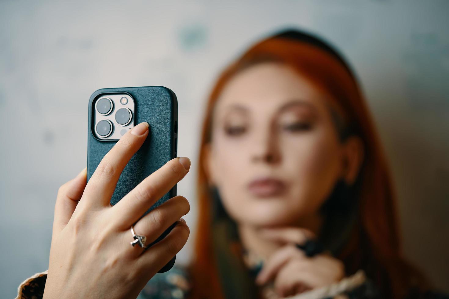 Red hair woman takes selfie on iPhone 13 pro. photo