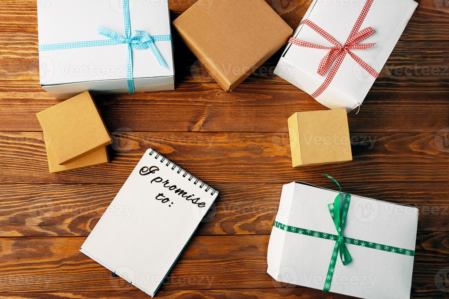 Top view of notebook and gift boxes on wooden table. photo