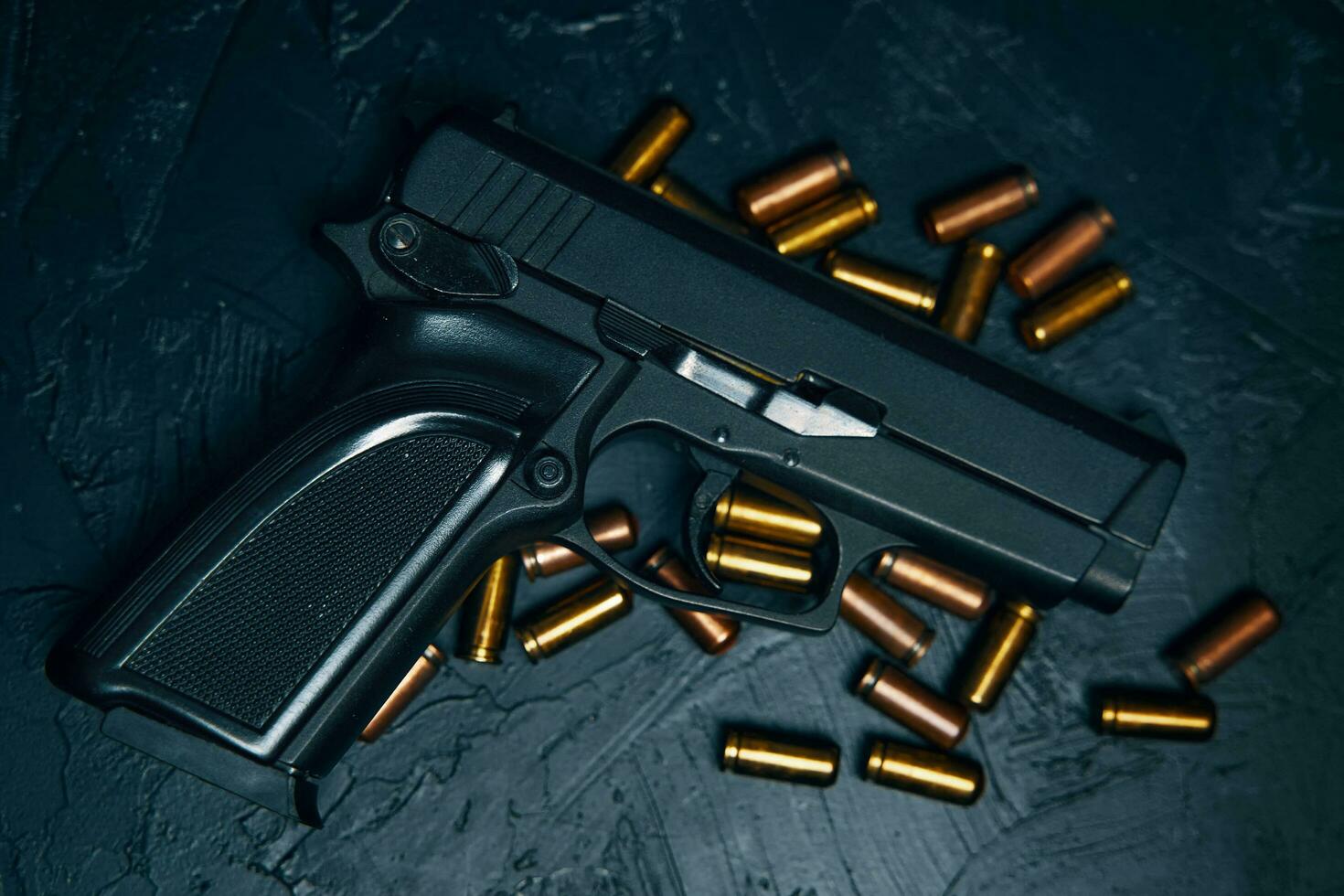 Gun with cartridges on dark concrete table. photo