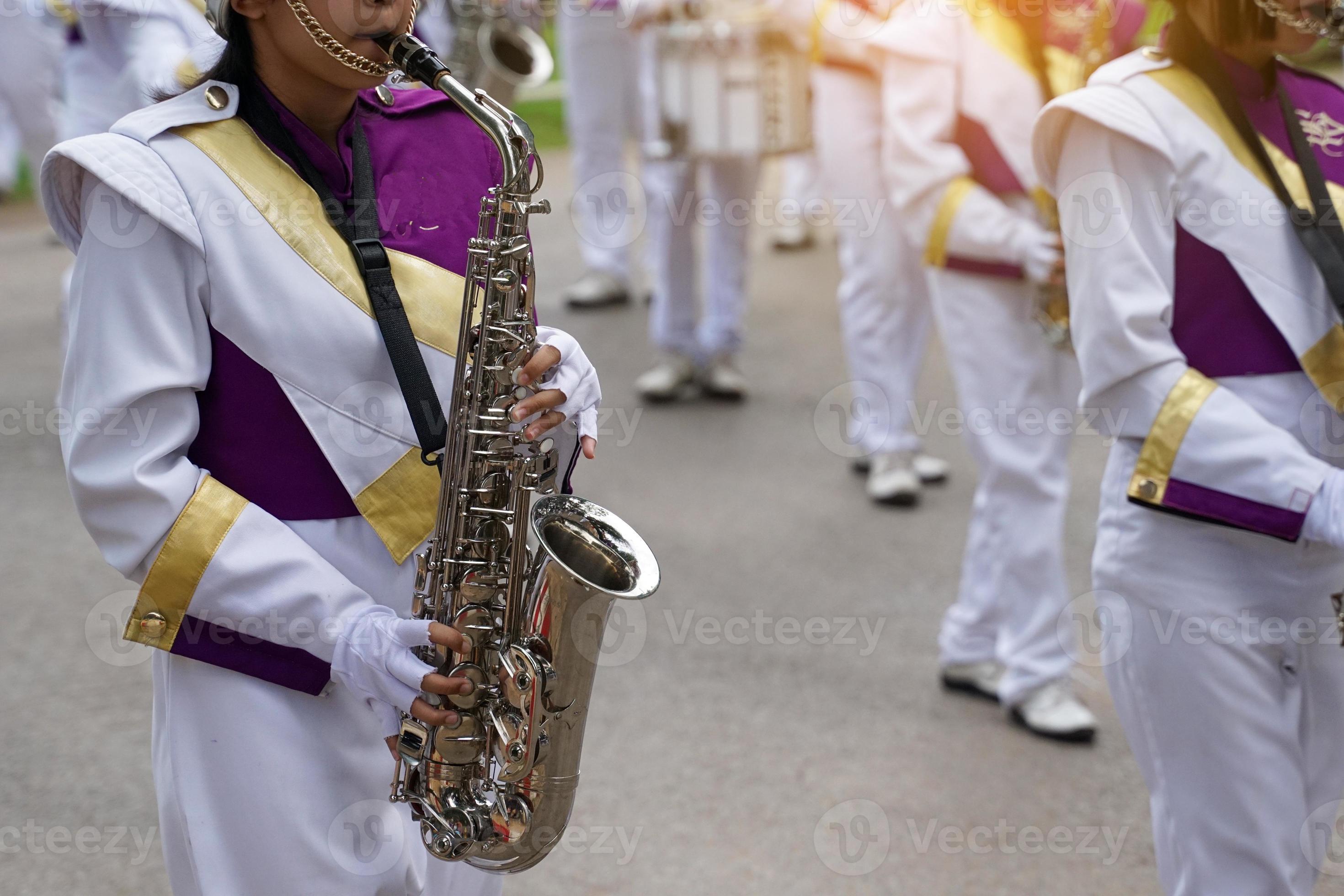 Orchestra students play saxophones in a parade at the school's