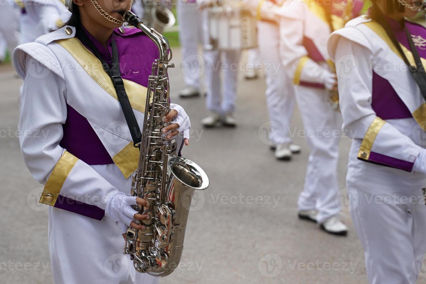 Orchestra students play saxophones in a parade at the school's athletics event. Soft and selective focus. photo