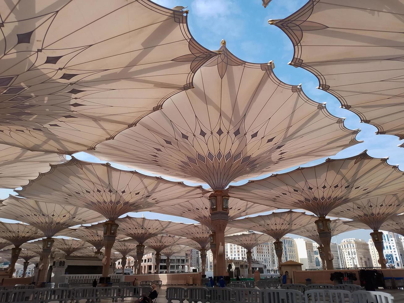 Medina, Saudi Arabia, 2022 - Umbrella construction on the square of Al-Masjid An-Nabawi or Prophet Muhammed Mosque are protecting people from sun at daytime and work as lights at night photo