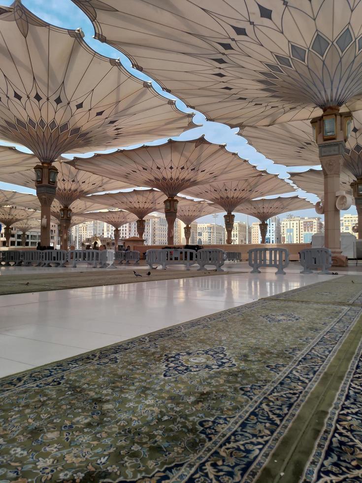 Medina, Saudi Arabia, 2022 - Umbrella construction on the square of Al-Masjid An-Nabawi or Prophet Muhammed Mosque are protecting people from sun at daytime and work as lights at night photo
