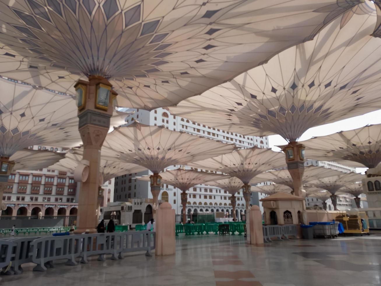 Medina, Saudi Arabia, 2022 - Umbrella construction on the square of Al-Masjid An-Nabawi or Prophet Muhammed Mosque are protecting people from sun at daytime and work as lights at night photo