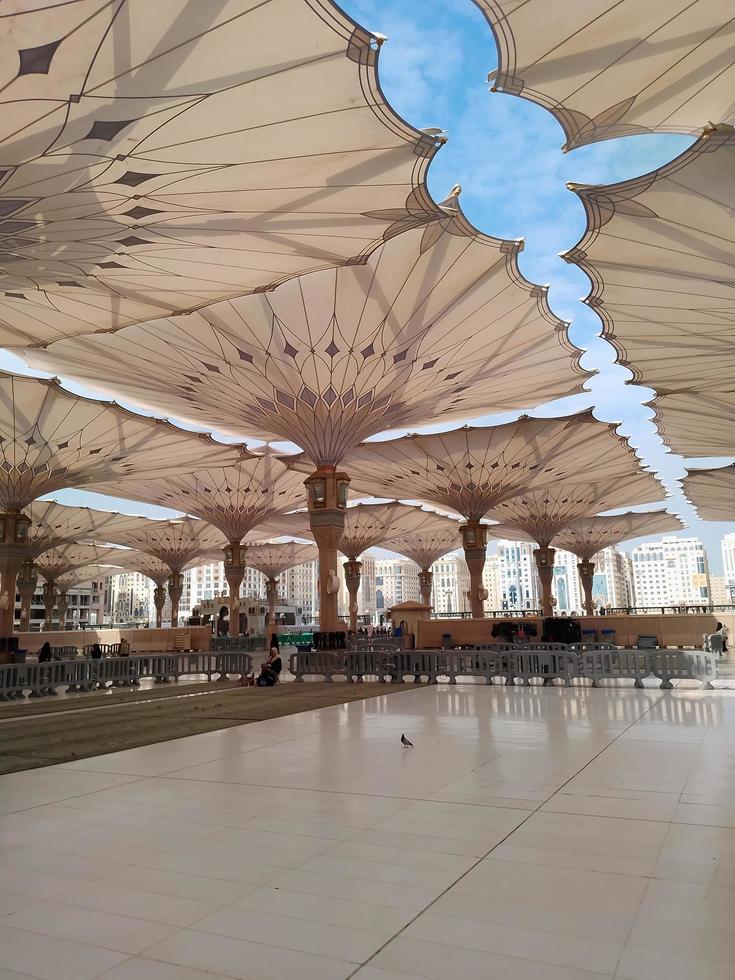 Medina, Saudi Arabia, 2022 - Umbrella construction on the square of Al-Masjid An-Nabawi or Prophet Muhammed Mosque are protecting people from sun at daytime and work as lights at night photo