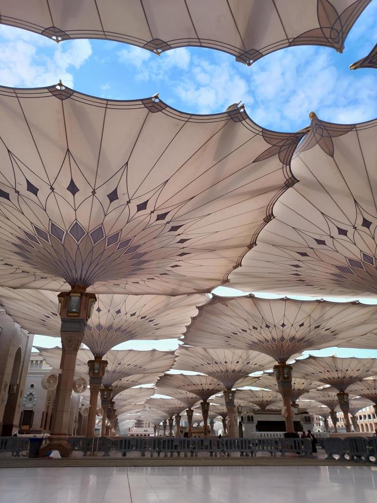 Medina, Saudi Arabia, 2022 - Umbrella construction on the square of Al-Masjid An-Nabawi or Prophet Muhammed Mosque are protecting people from sun at daytime and work as lights at night photo