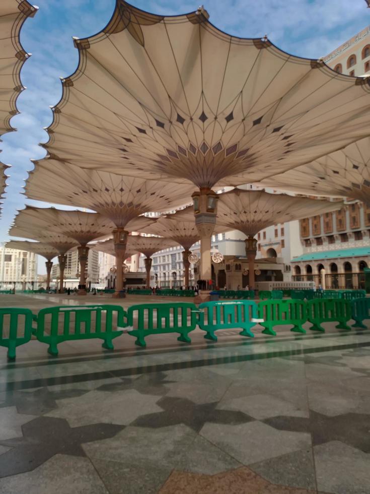 Medina, Saudi Arabia, 2022 - Umbrella construction on the square of Al-Masjid An-Nabawi or Prophet Muhammed Mosque are protecting people from sun at daytime and work as lights at night photo