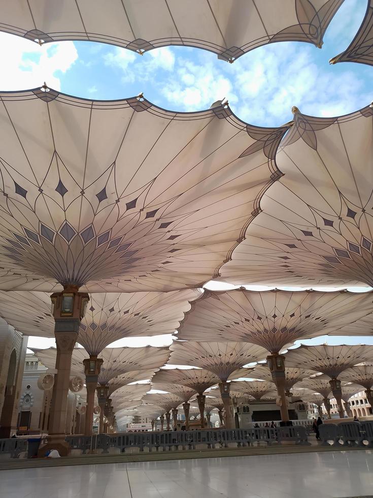 Medina, Saudi Arabia, 2022 - Umbrella construction on the square of Al-Masjid An-Nabawi or Prophet Muhammed Mosque are protecting people from sun at daytime and work as lights at night photo