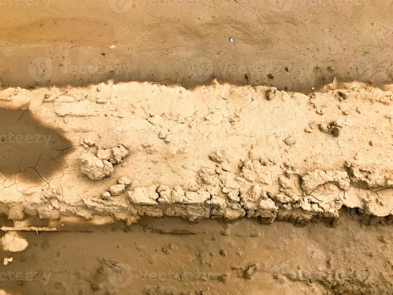 Texture of a dirty bad dirt road dirt road with puddles and clay drying mud with cracks and ruts. Off-road. The background photo