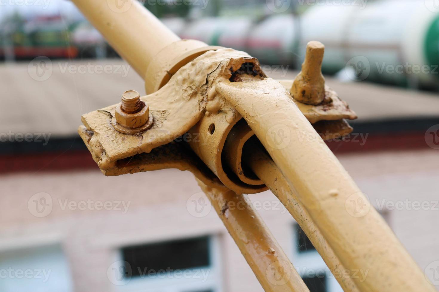 The metal sturdy fastening of the two iron yellow sticks of the rods with the help of bolts pins the studs and clamp photo