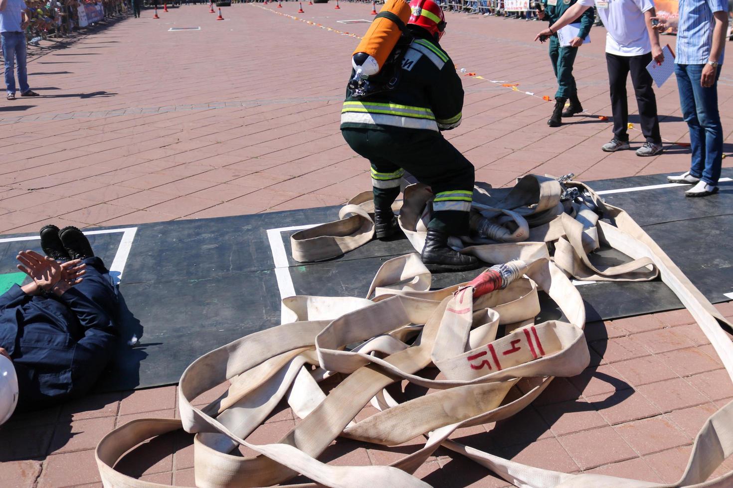 Men fire in a black fireproof suit and a helmet with a balloon runs with hoses, fire hoses to save people photo