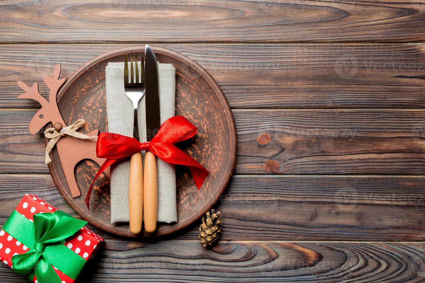 Top view of plate, fork and knife served on Christmas decorated wooden background. New Year Eve concept with copy space photo