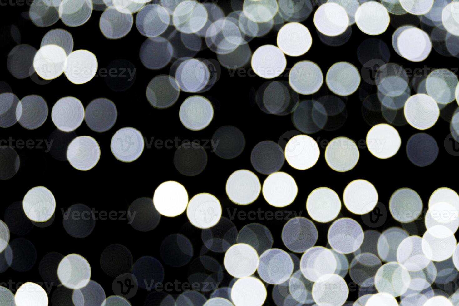 Bokeh white lights on black background, defocused and blurred many round light on background photo