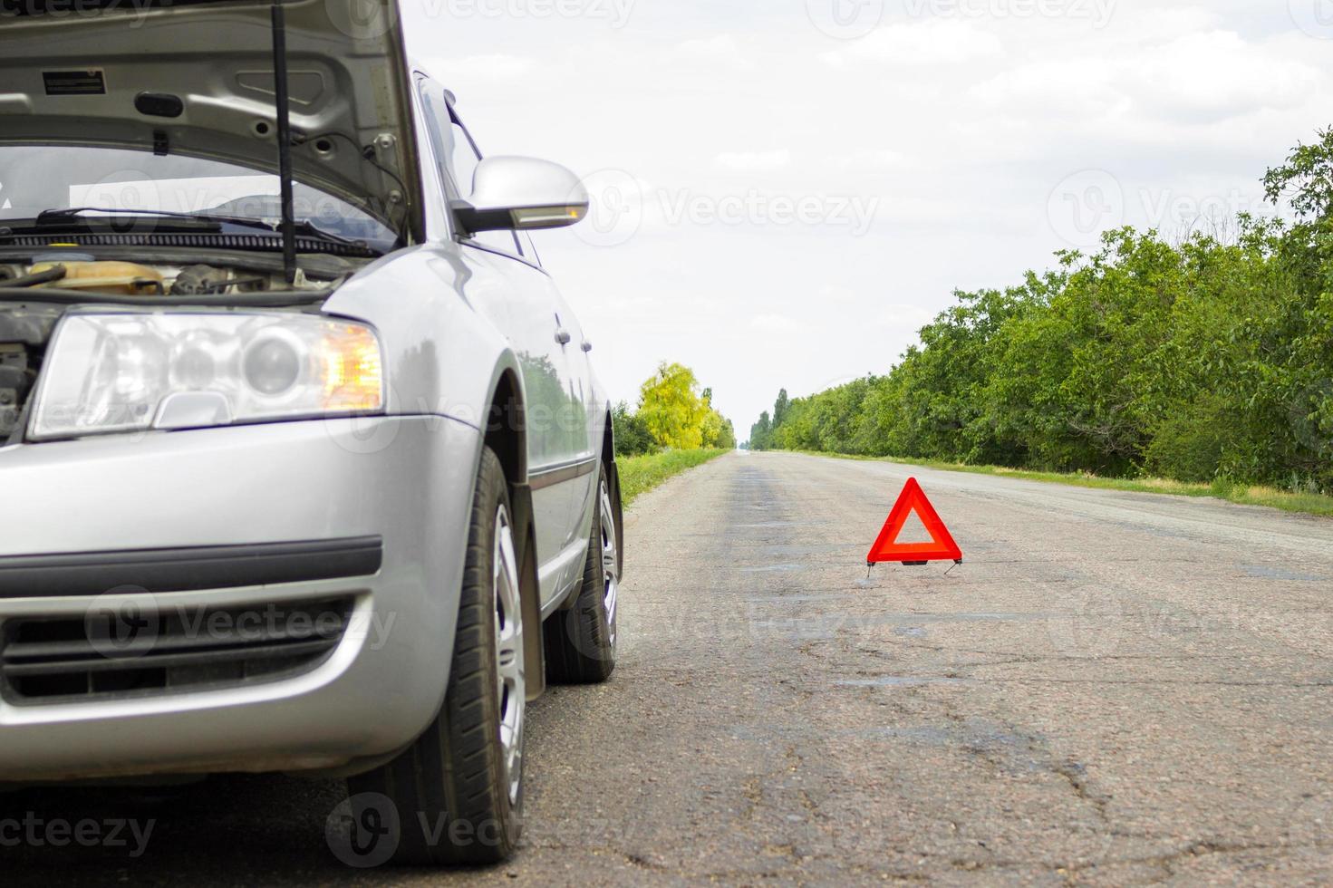 Red triangle of a car on the road. Car warning triangle on the road against the city in the evening. photo