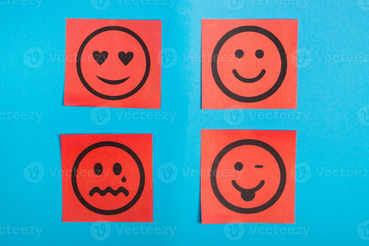 Red paper with faces with emotions on a blue board, message board . Paper stick. photo