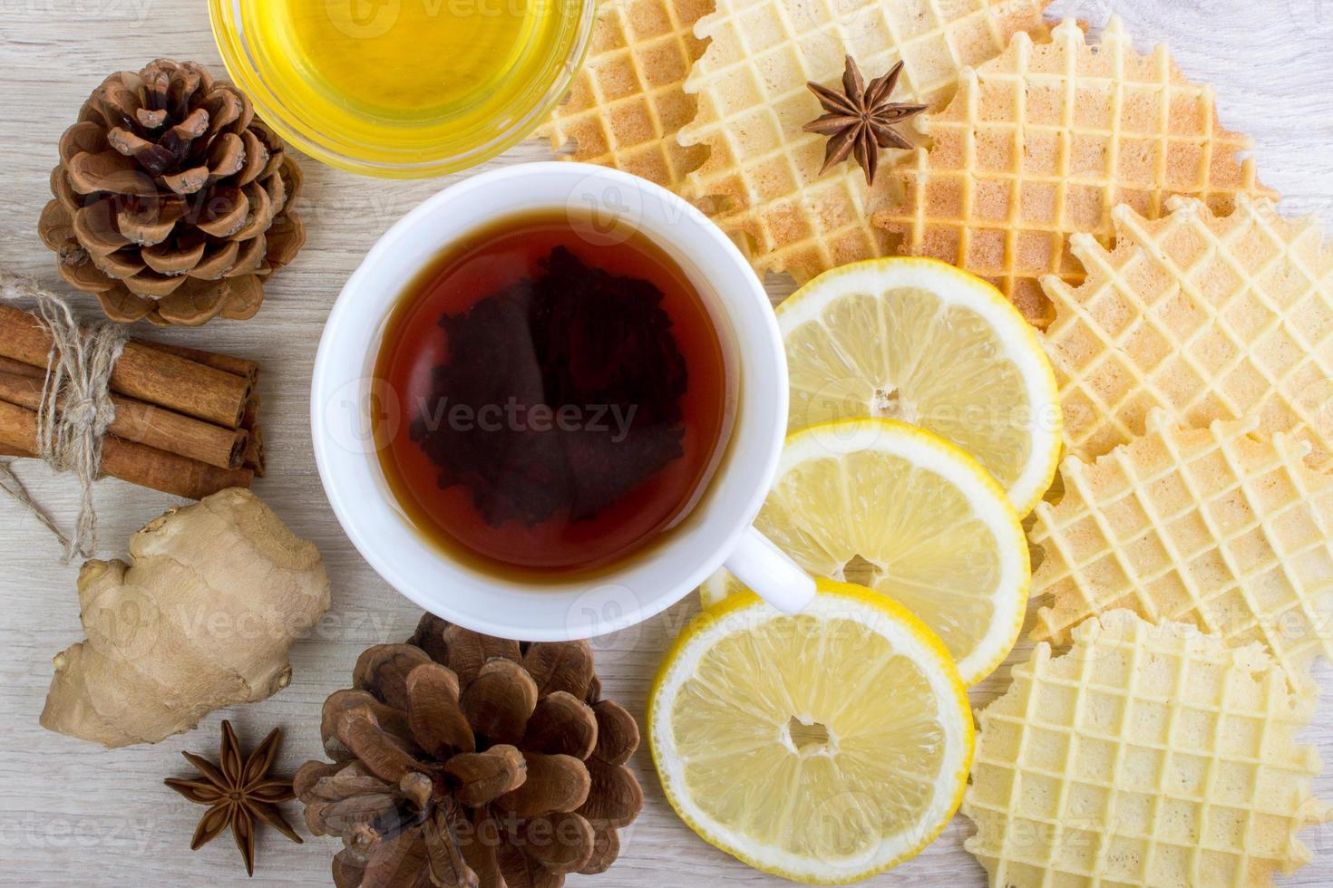 Cup of tea with honey, pinecone, badian, ginger, waffles and cinnamon photo