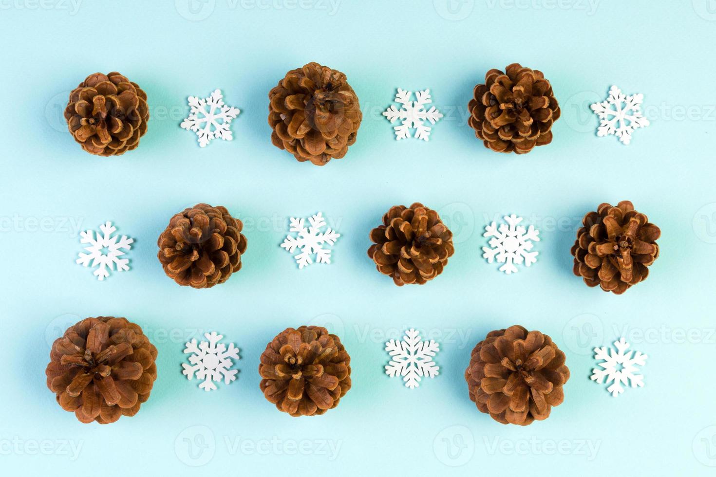 Top view of holiday composition made of pine cones and white snowflakes on colorful background. Winter time and Christmas concept with copy space photo