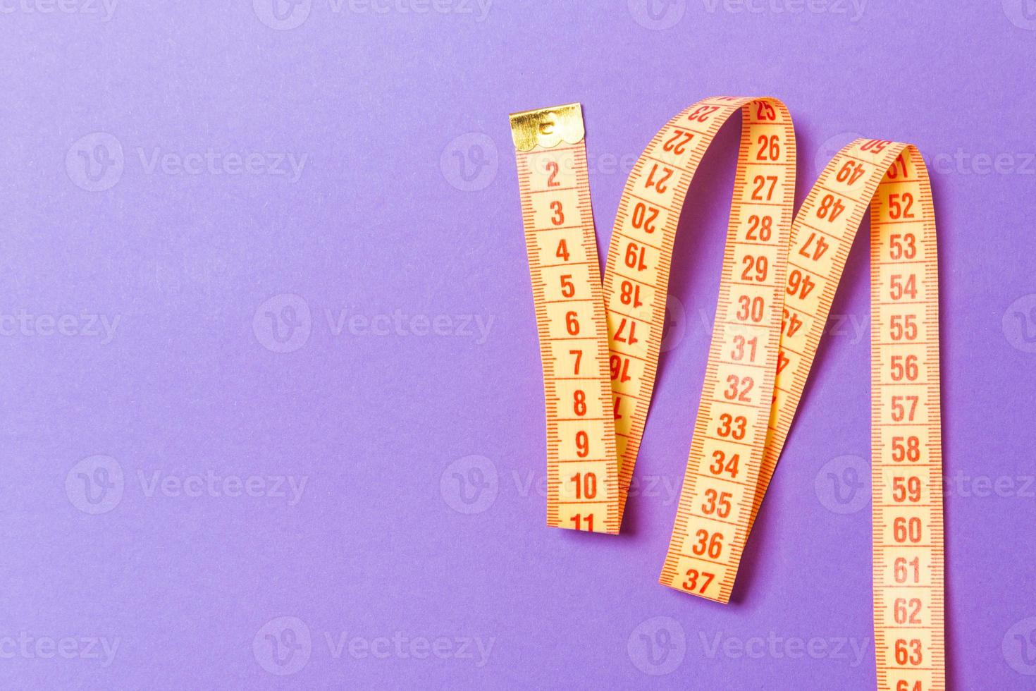 Top view of measuring tape on purple background. Tailor and slim waist concept with emty space for your idea photo