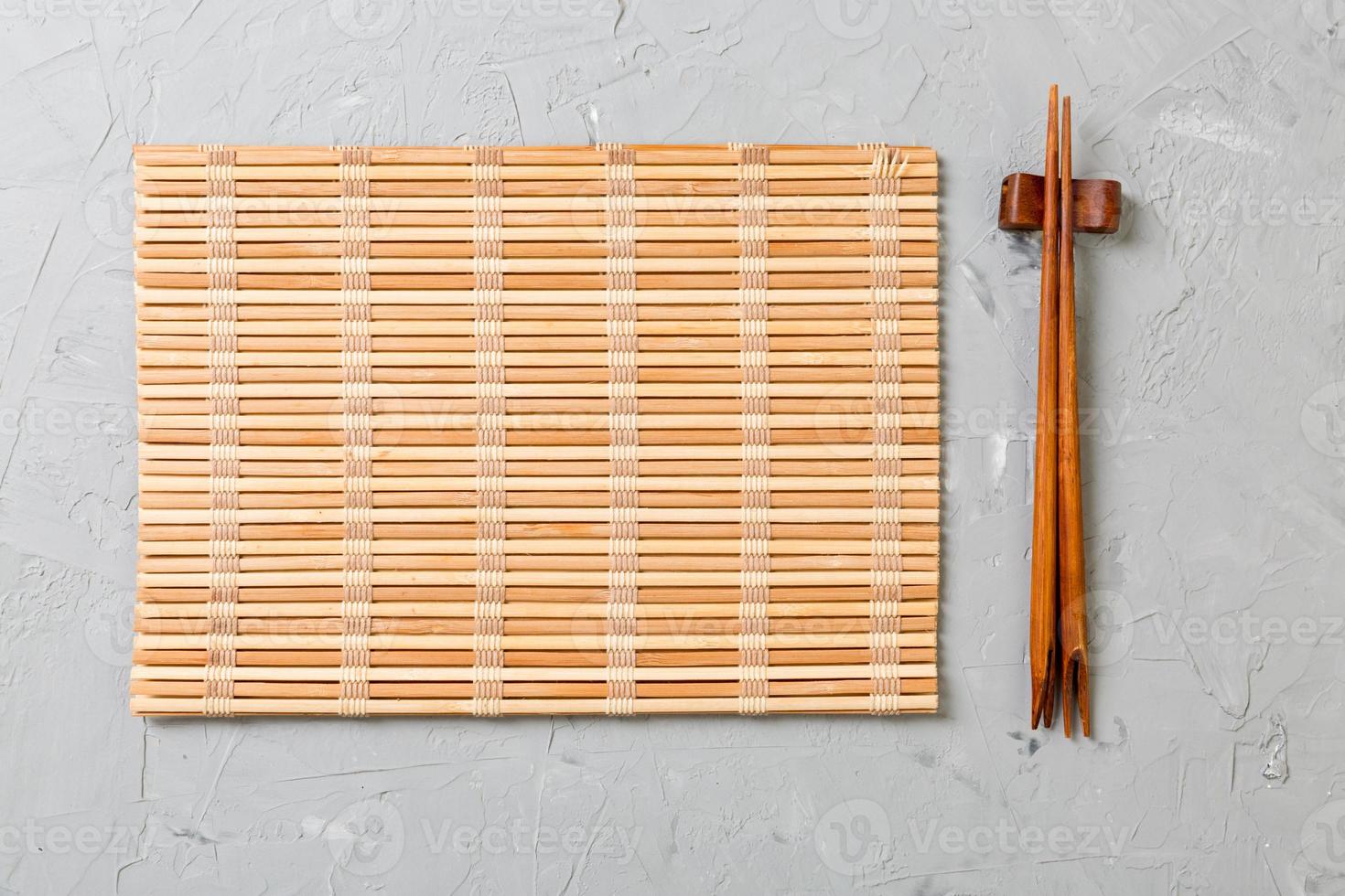 two sushi chopsticks with empty bamboo mat or wood plate on stone Background Top view with copy stace photo