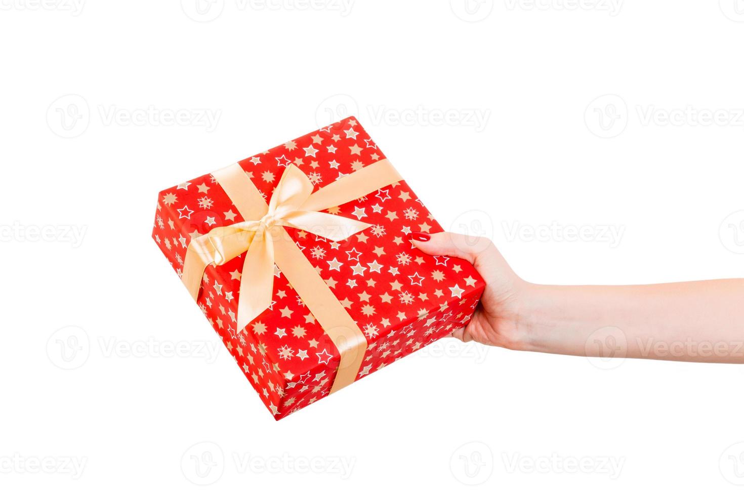 Woman hands give wrapped Christmas or other holiday handmade present in red paper with Gold ribbon. Isolated on white background, top view. thanksgiving Gift box concept photo