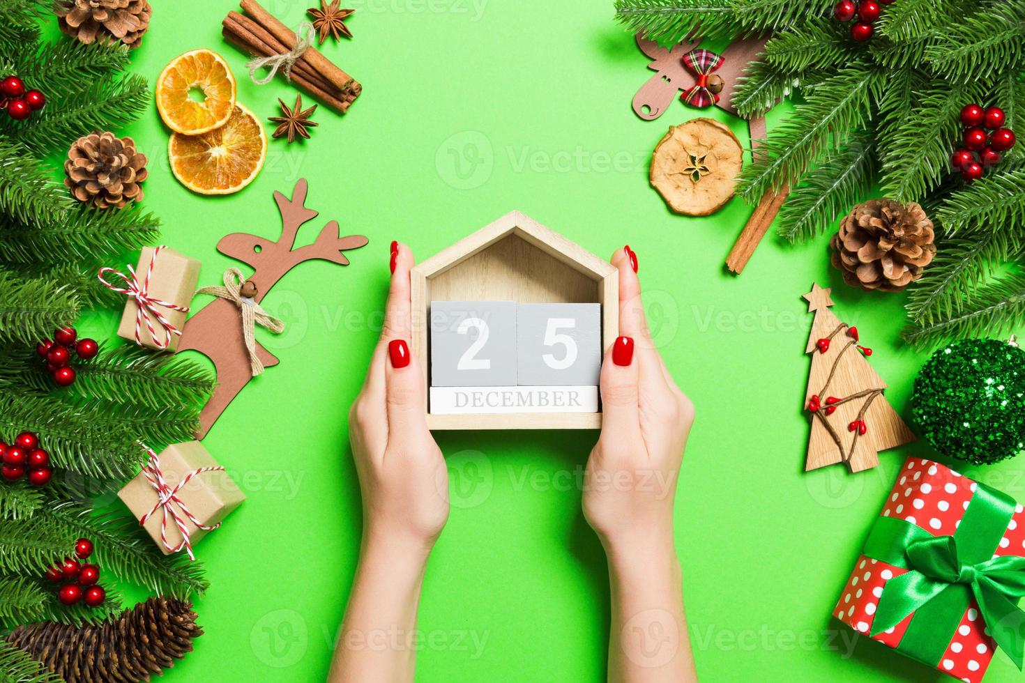 Top view of female hands holding calendar on green background. The twenty fifth of December. Holiday decorations. Christmas time concept photo