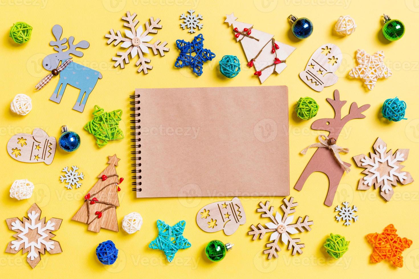 Top view of notebook on yellow background with New Year toys and decorations. Christmas time concept photo