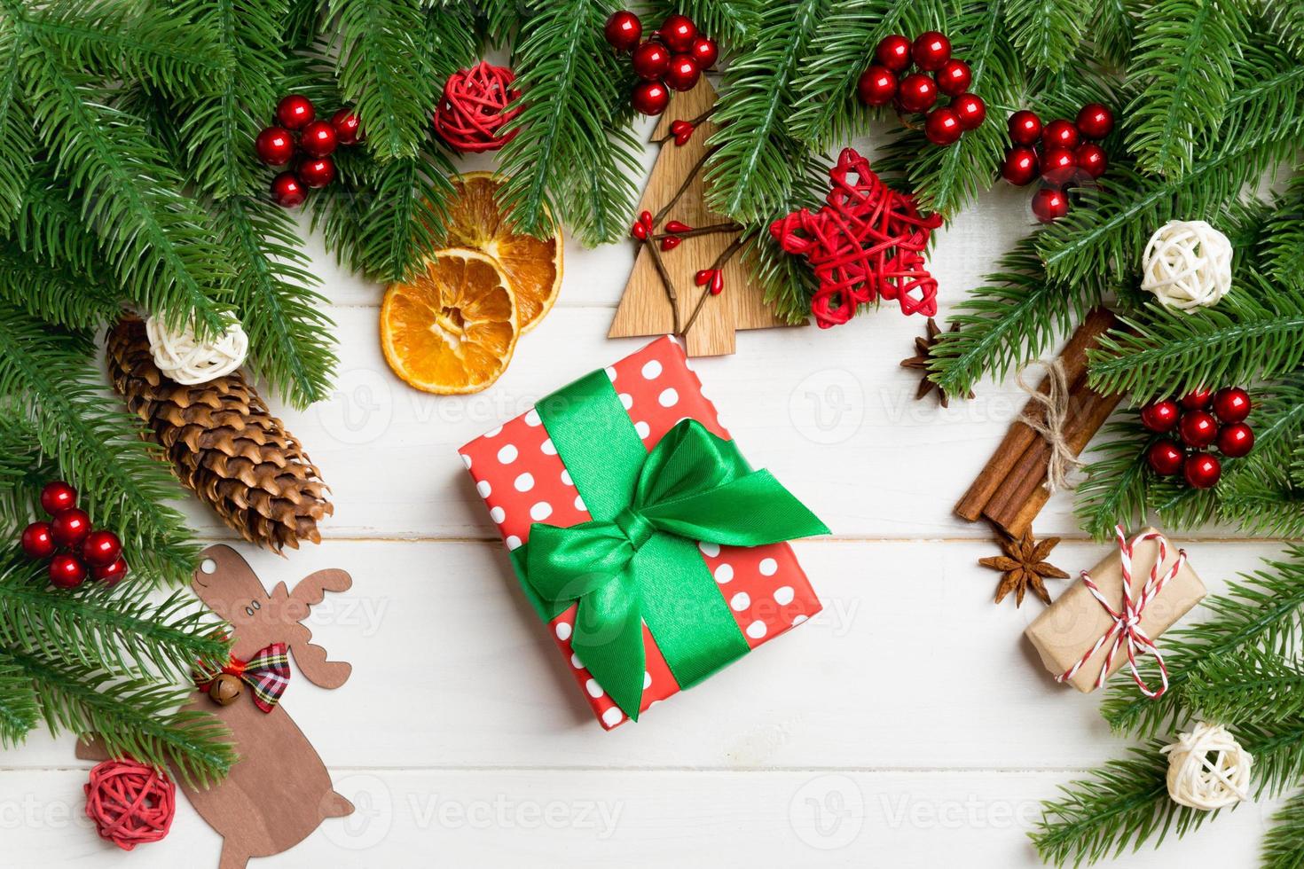 Top view of fir tree branches, gift and festive decorative toys on wooden background. New Year time concept photo