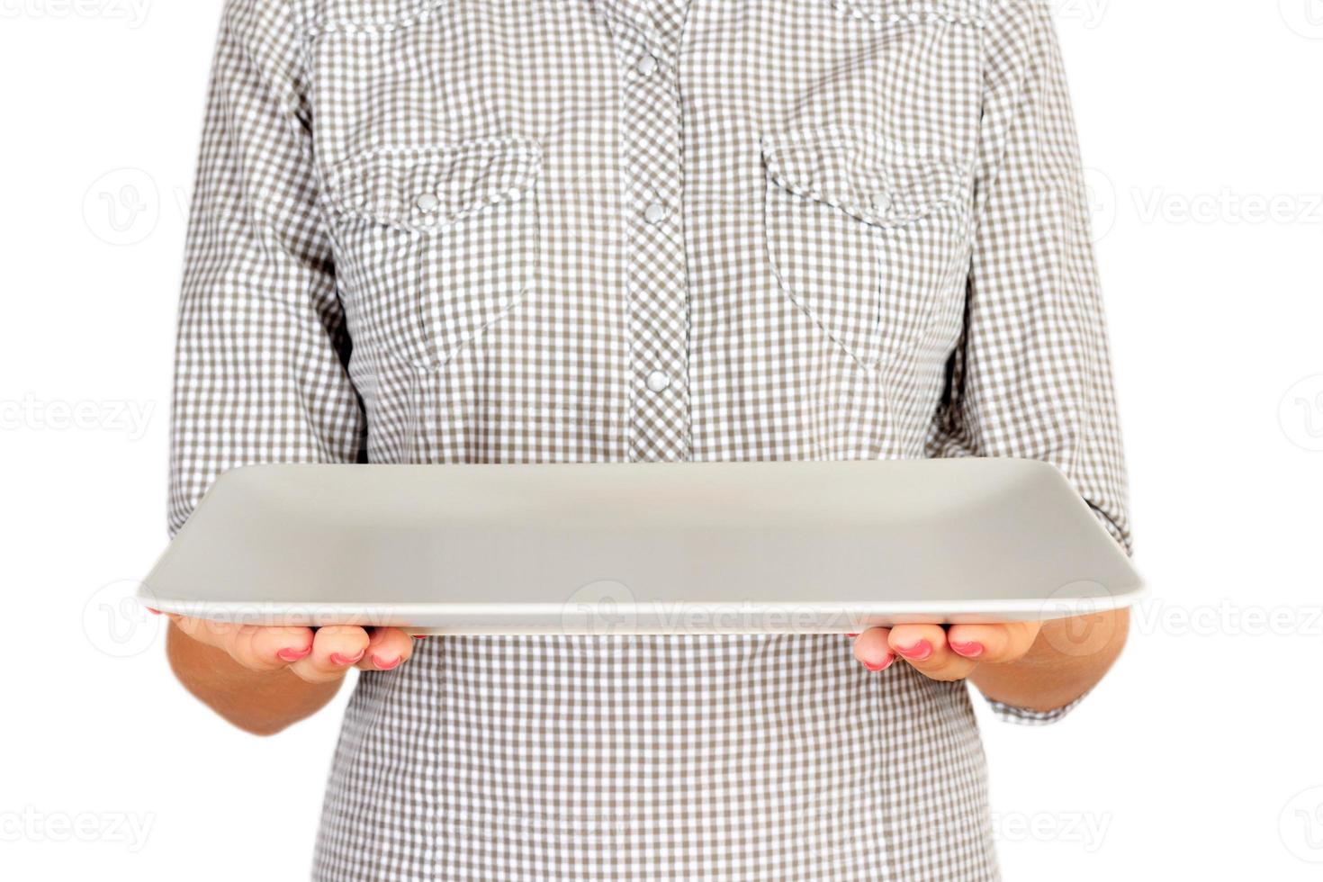 girl in the plaid shirt is holding an empty rectangular matte plate in front of her. woman hand hold empty dish for you desing. perspective view, isolated on white background photo