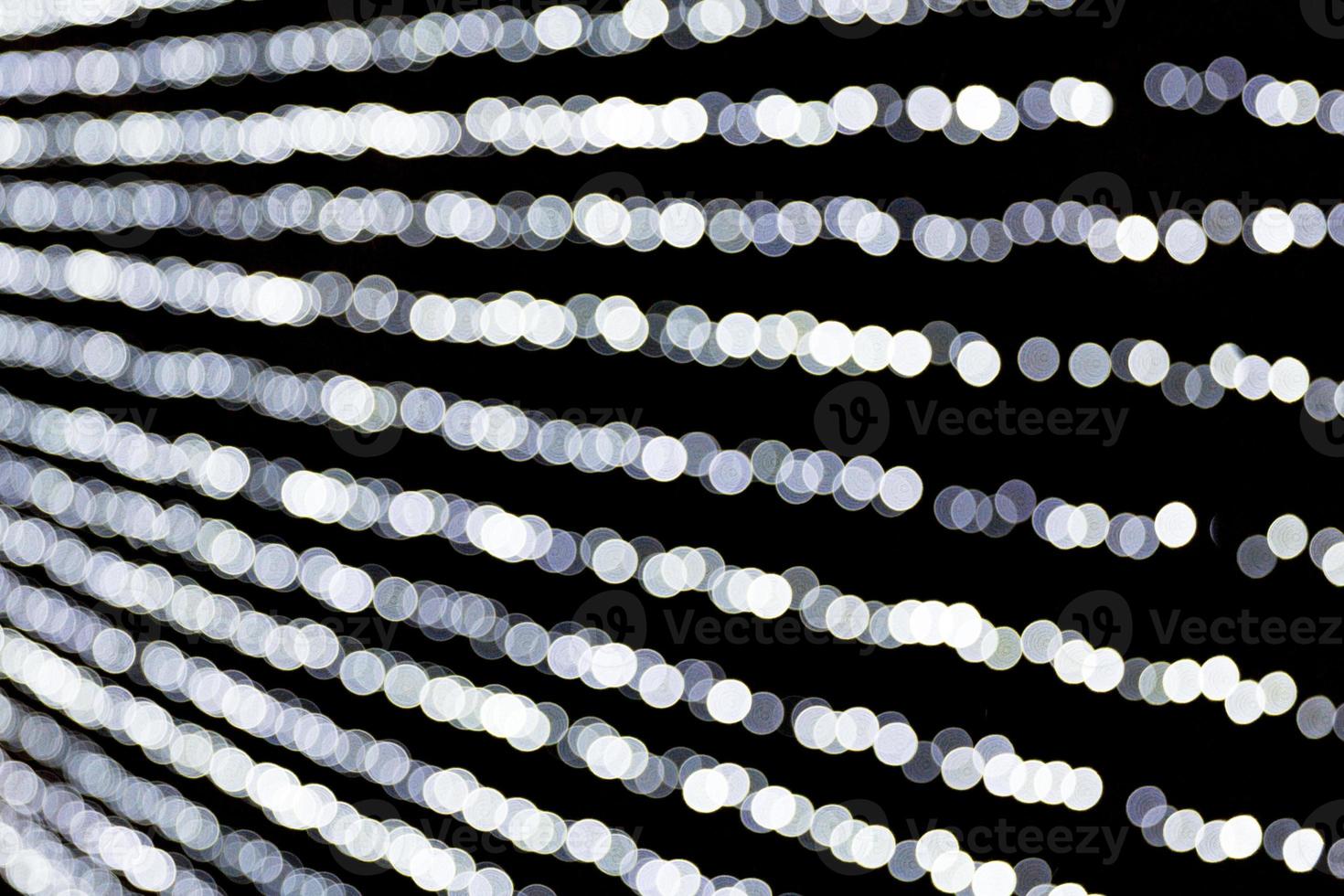 Bokeh white lights on black background. Abstract defocused many round light photo