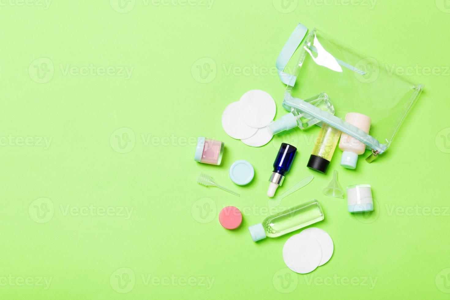 Top view of means for face care bottles and jars of tonic, micellar cleansing water, cream, cotton pads on green background. Bodycare concept with empty cpace for your ideas photo