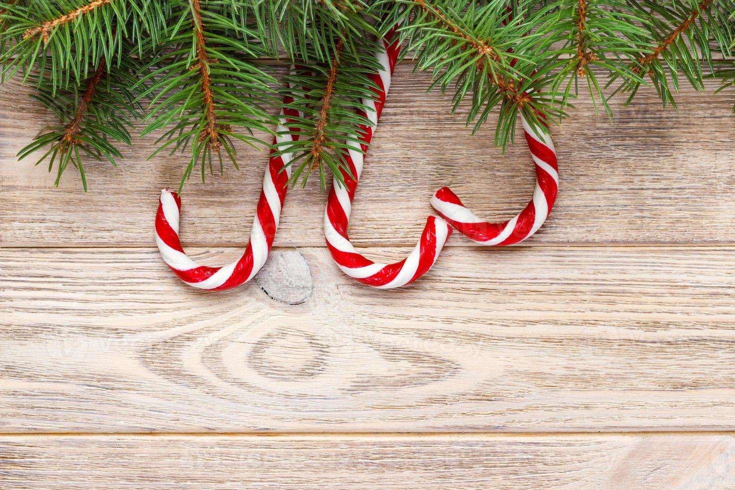 Christmas fir tree branches with candy cane on white rustic wooden background with copy space for text photo