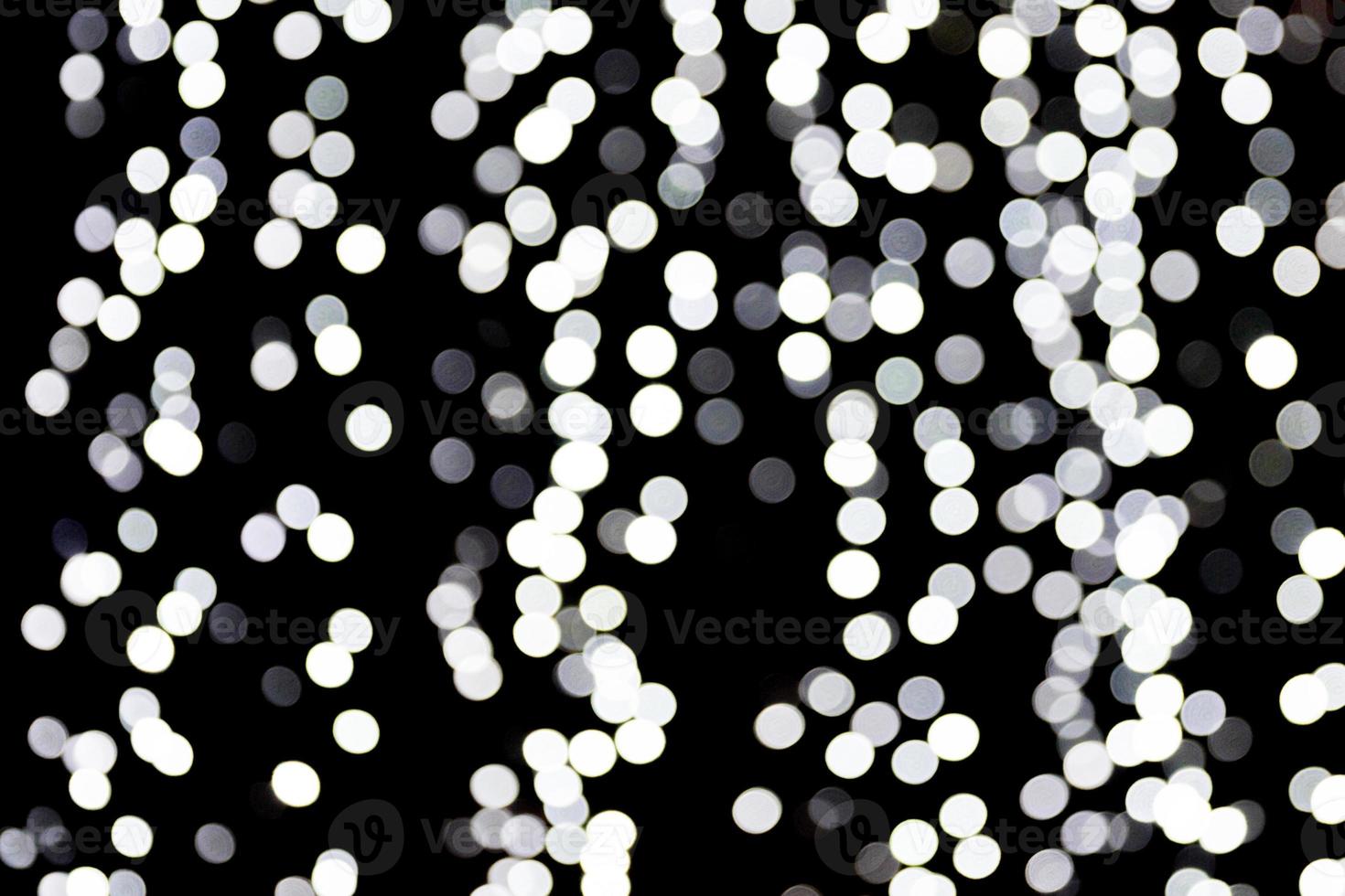Abstract bokeh of white lights on black background. defocused and blurred many round light photo
