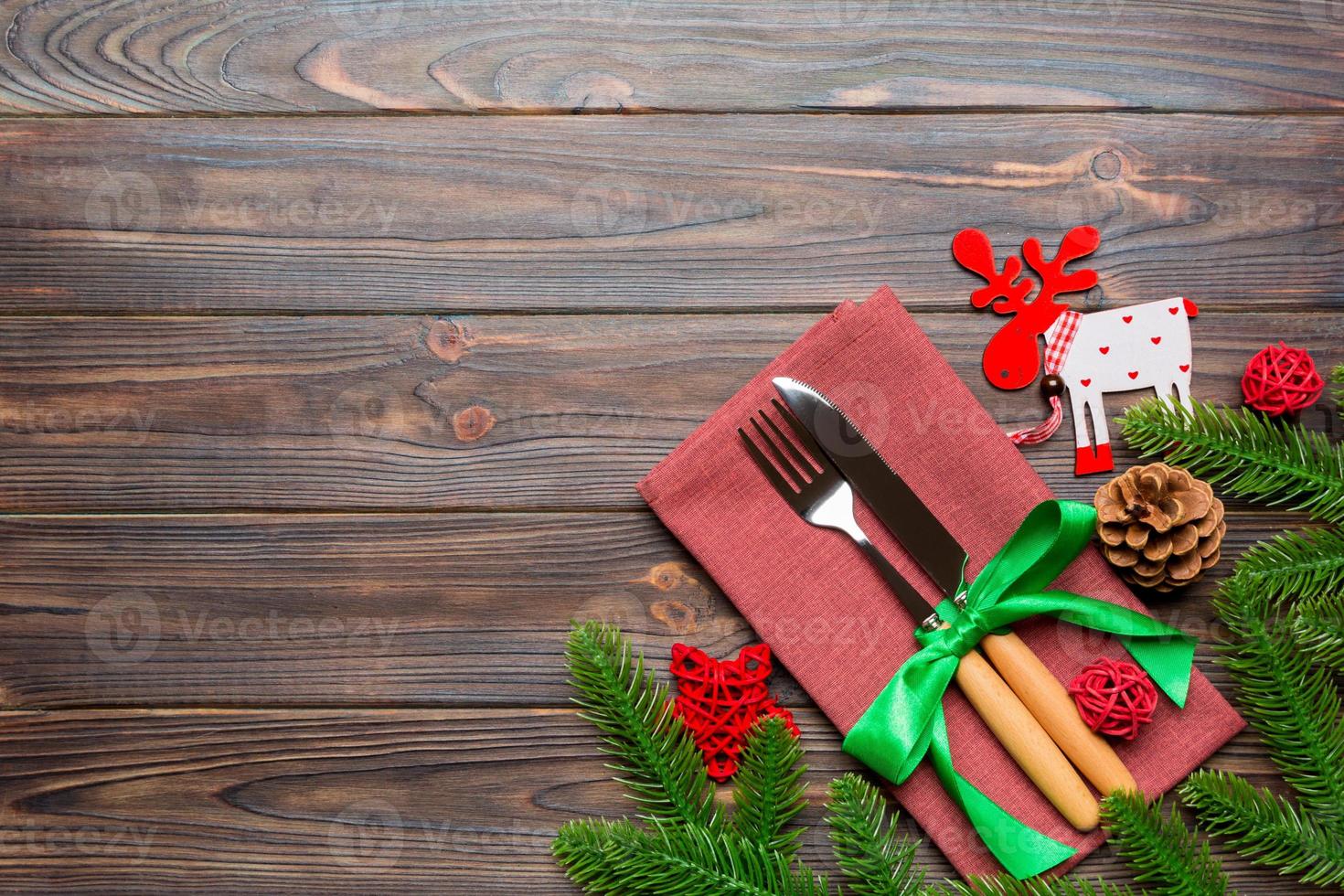 Top view of flatware tied up with ribbon on napkin on wooden background. Christmas decorations and reindeer with empty space for your design. New Year holiday concept photo
