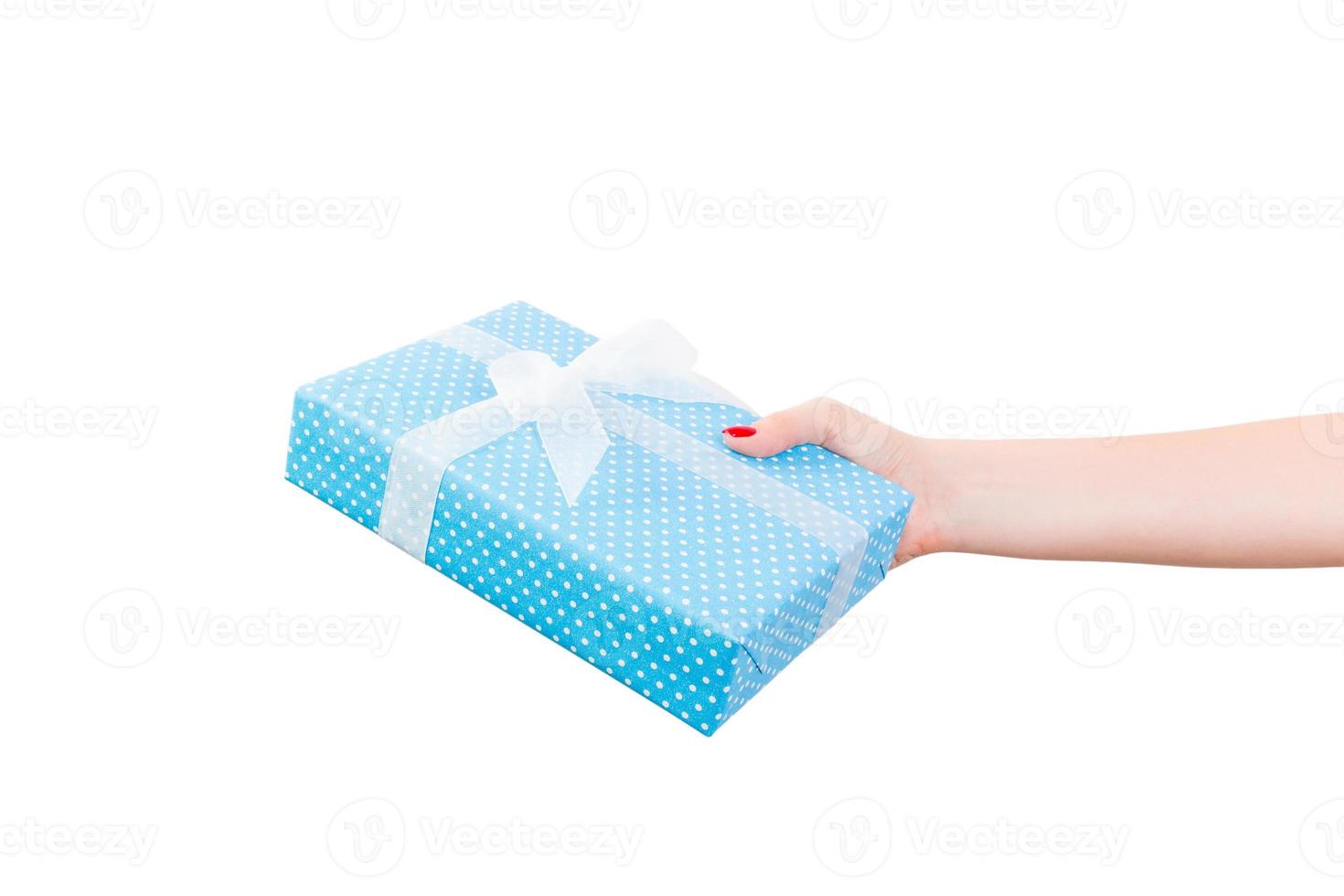 Woman hands give wrapped Christmas or other holiday handmade present in blue paper with white ribbon. Isolated on white background, top view. thanksgiving Gift box concept photo