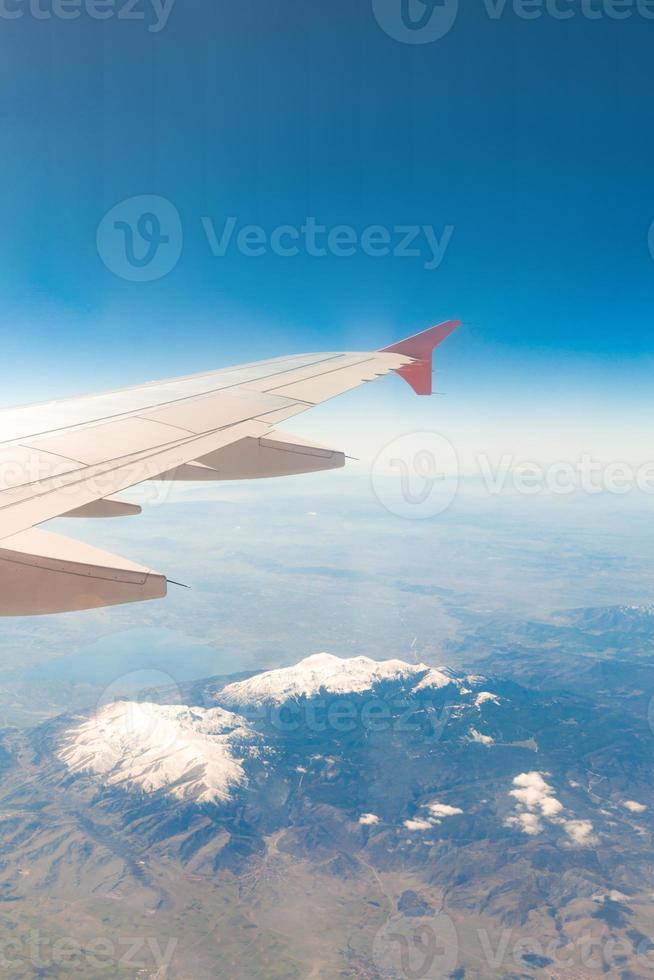 view from the window of the plane that flies over the mountains photo