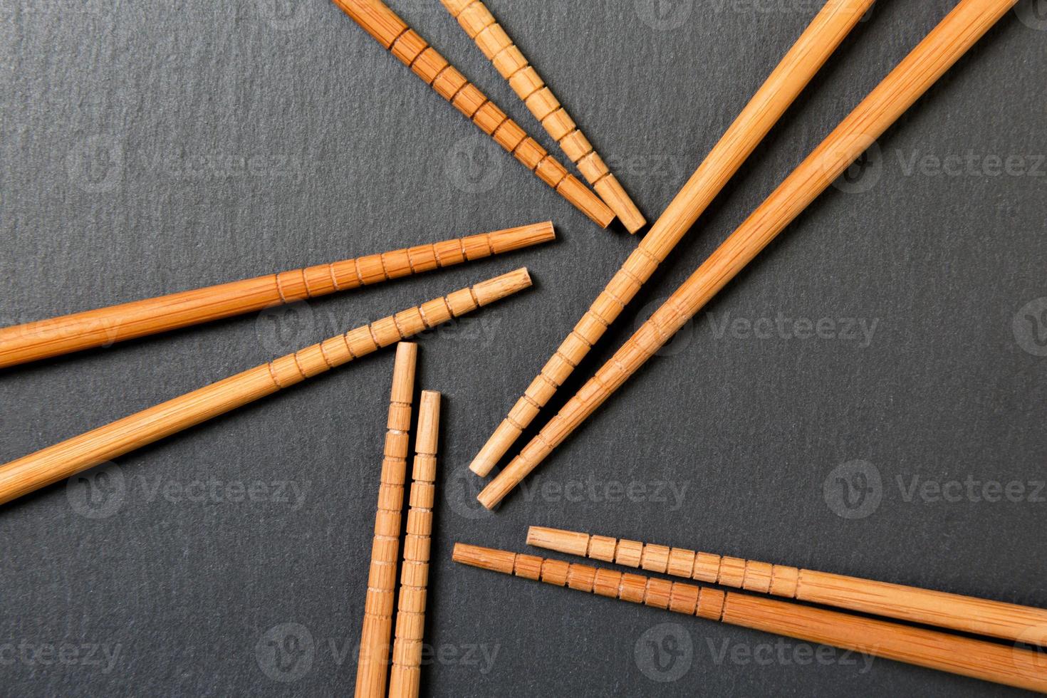 Many bamboo chopsticks on black slate background, textured, top view with opy space photo