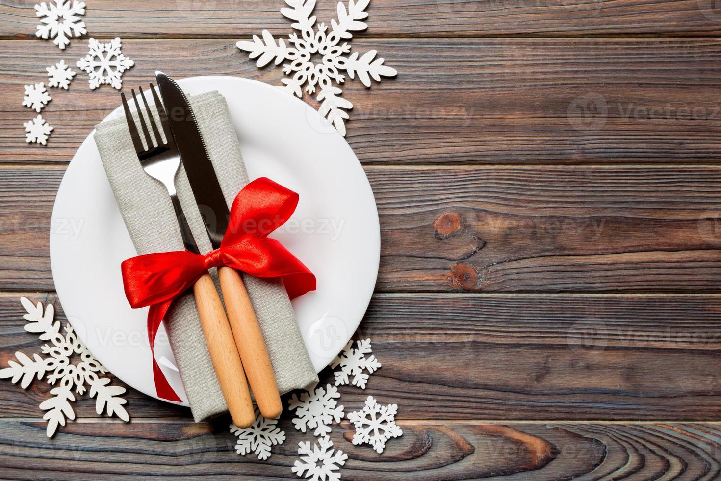 Top view of plate, fork and knife served on Christmas decorated wooden background. New Year Eve concept with copy space photo