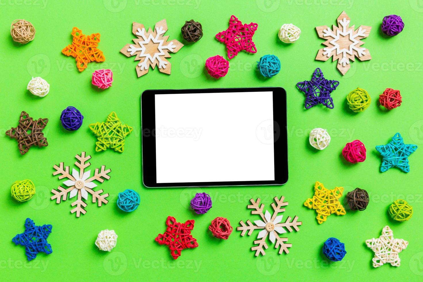 Top view of digital tablet. New Year decorations on green background. Festive stars and balls. Merry Christmas concept photo