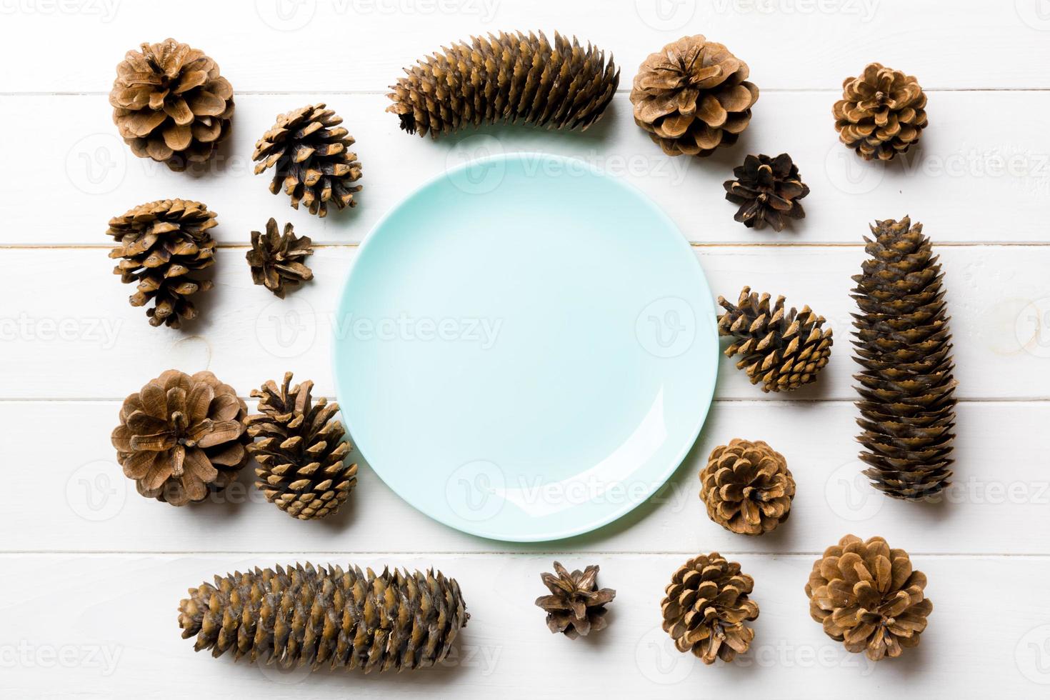 Top view of festive plate with pine cones on wooden background. New Year dinner concept photo