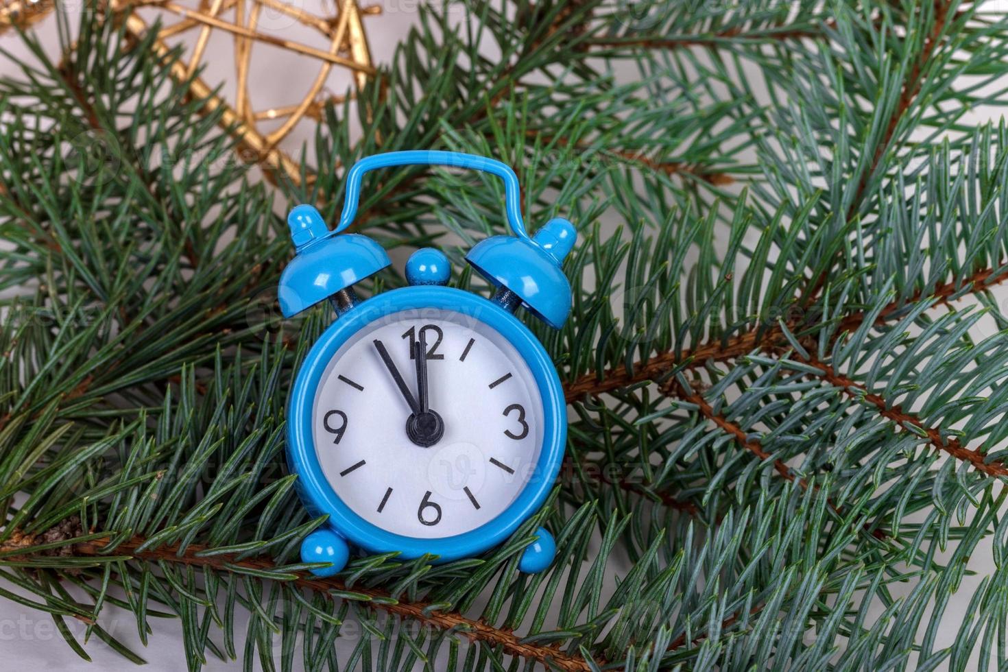 Christmas fir tree branches with alarm clock on rustic wooden background with copy space photo
