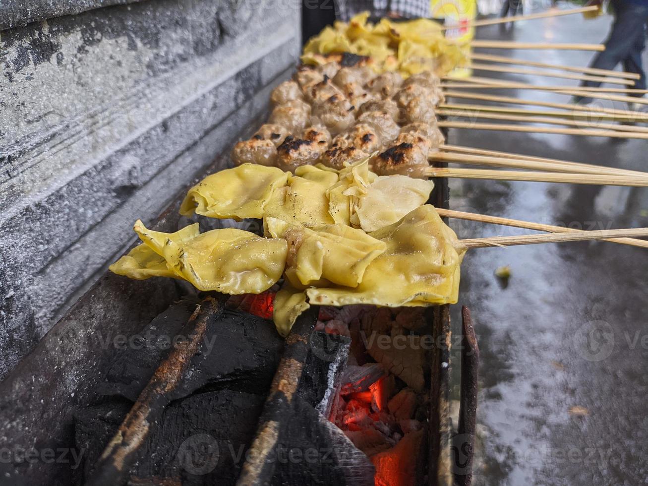 albóndigas a la parrilla. comida local tradicional de la calle en indonesia donde el proceso de fabricación se asa a la parrilla con carbón caliente foto