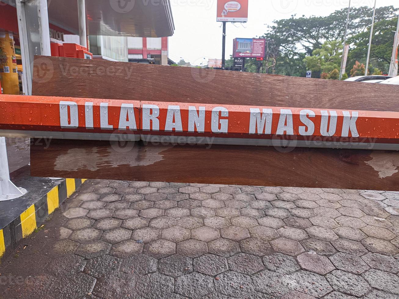 A sign that reads dilarang masuk says No Entry in Indonesian in the mall parking lot photo